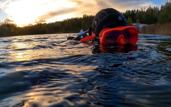 Elena Gushchina (lol2o) in a pink mask and a hood on the surface of a lake in Finland
