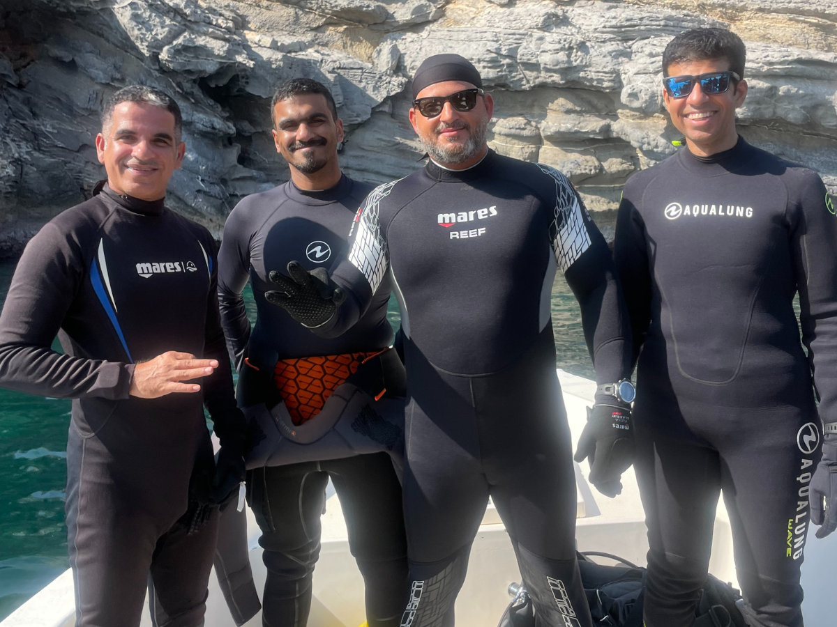 khalid alrazooqi standing on a dive boat with three other divers