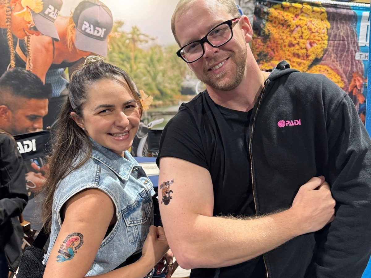Two divers showing off their ocean-themed temporary tattoos in a dive show