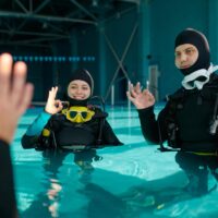 divers in a pool using ok sign