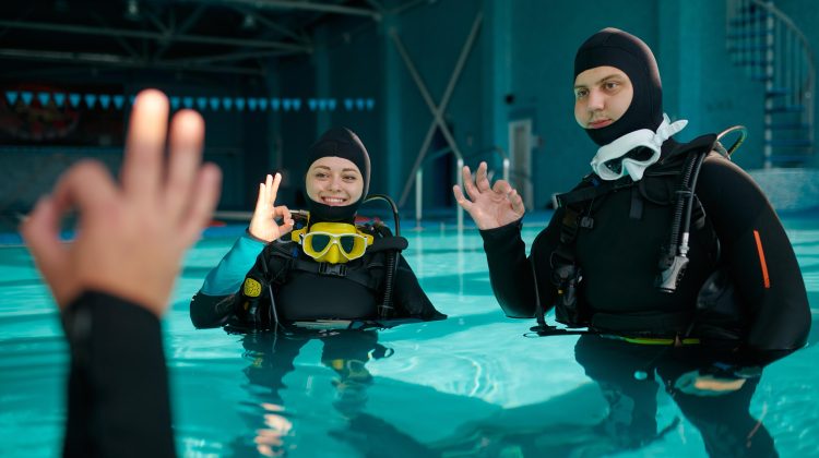 divers in a pool using ok sign