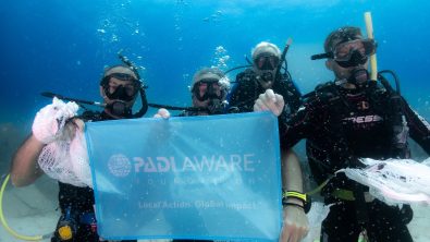 four divers carrying Dive Against Debris bags holding up a