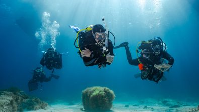 5 divers swim underwater in Malta