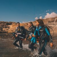 three divers walk int oth eocean together in Tenerife, Canary Islands, Spain