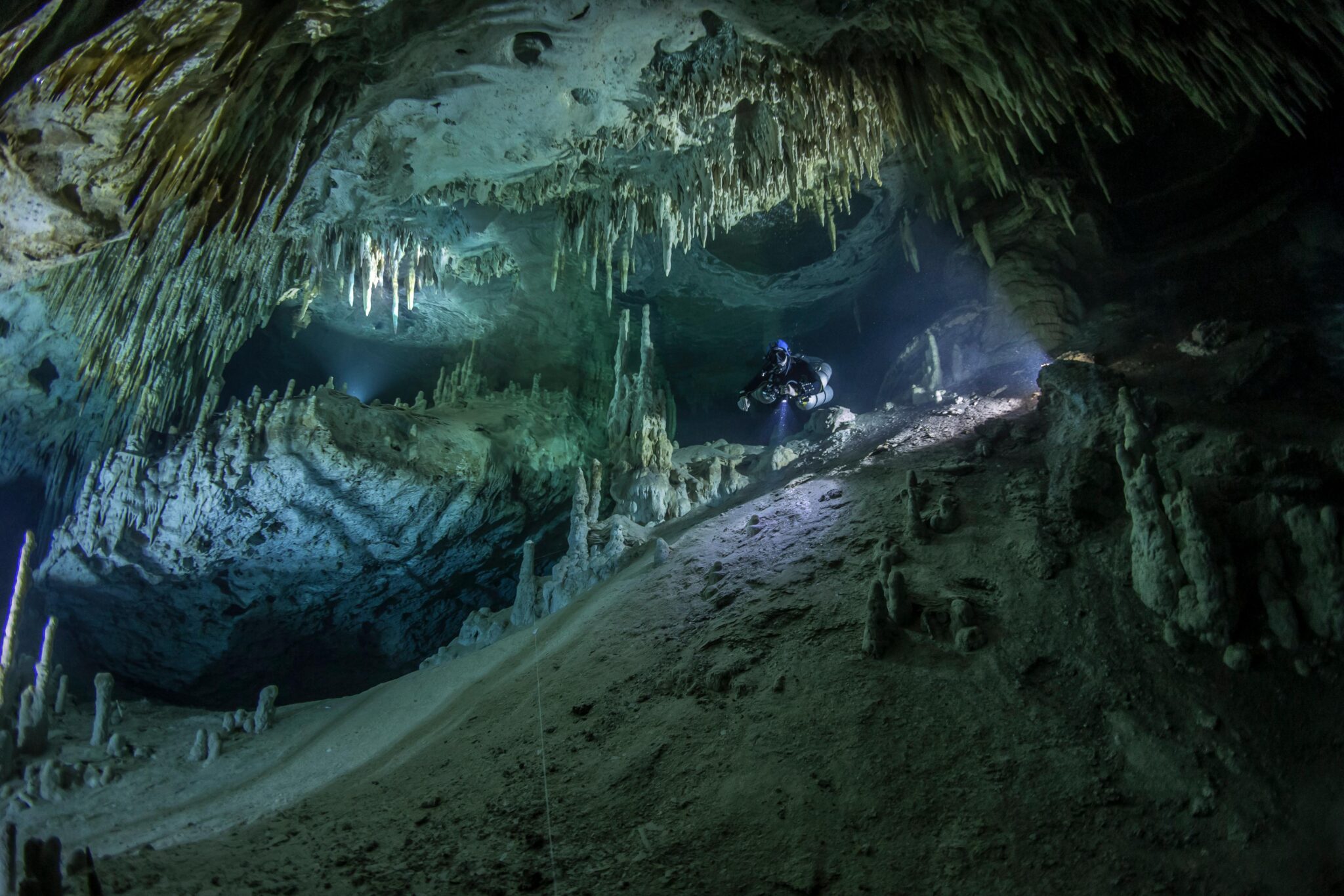 diver gliding through underwater cave cenote