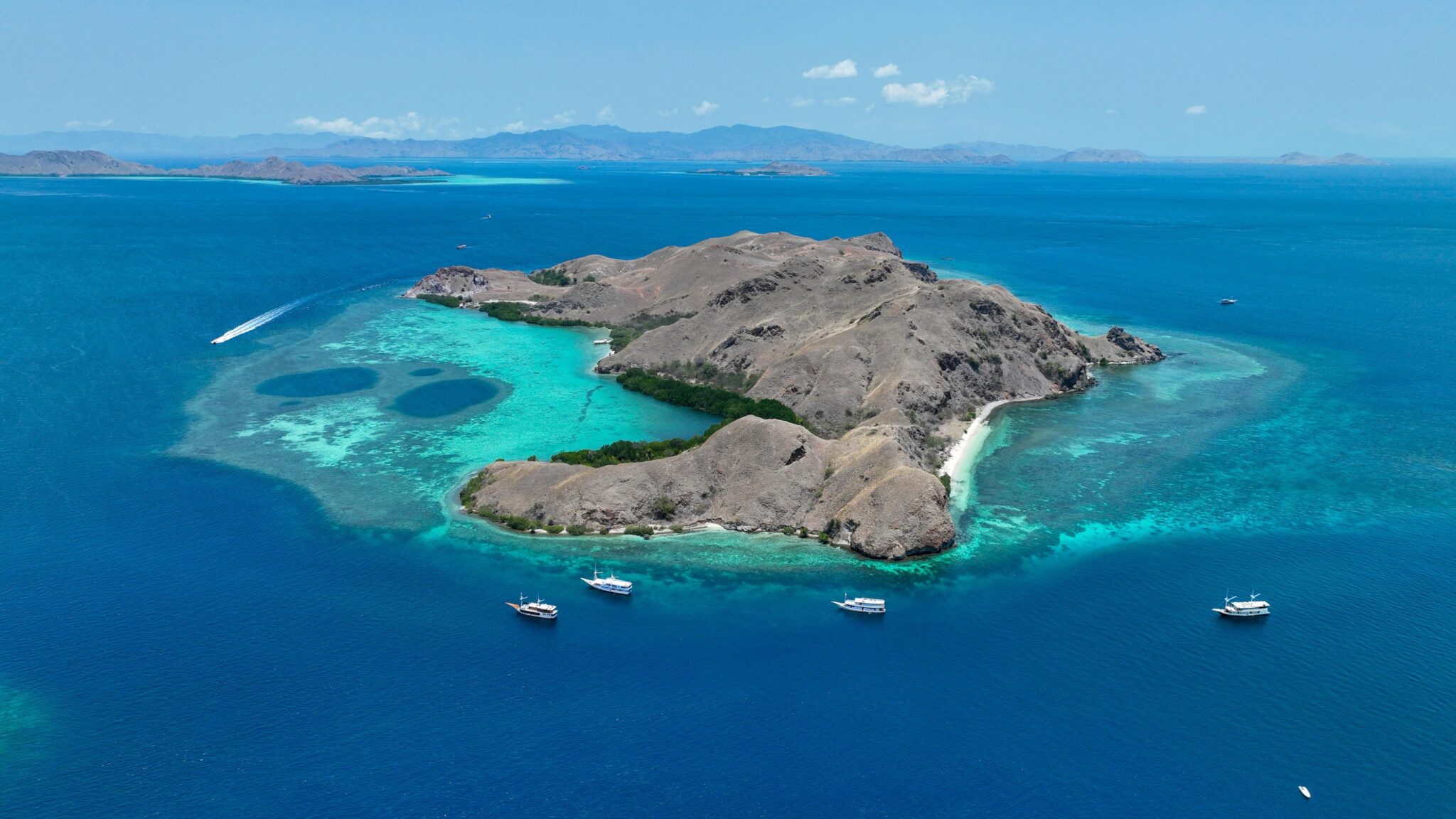 drone shot of several liveaboards next to an island