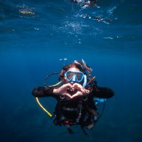 Diver underwater facing the camera making a heart shape with her hands