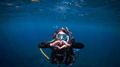 Diver underwater facing the camera making a heart shape with her hands