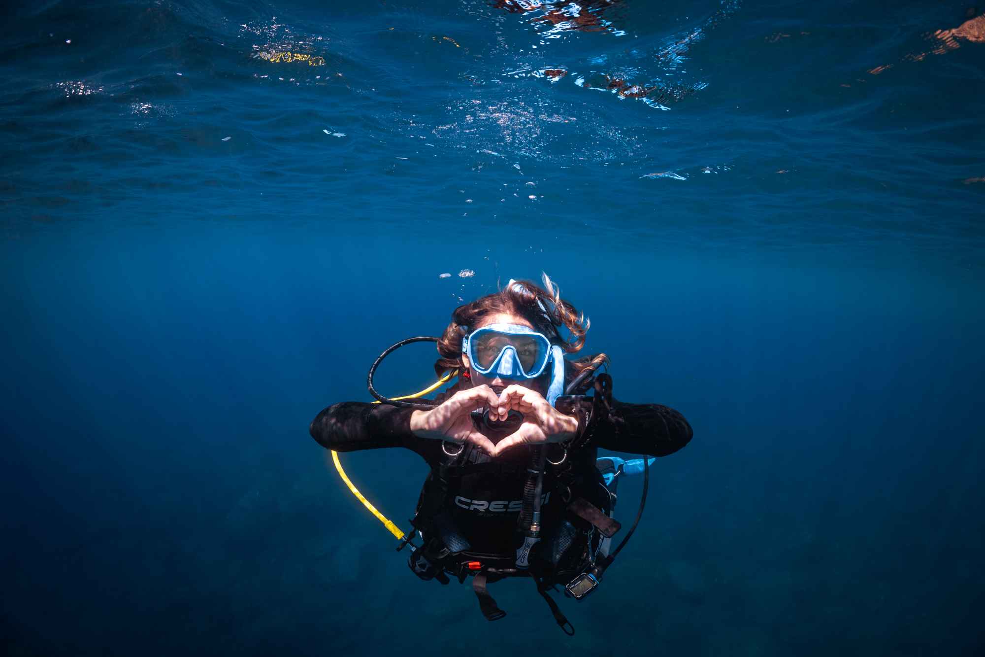 Diver underwater facing the camera making a heart shape with her hands