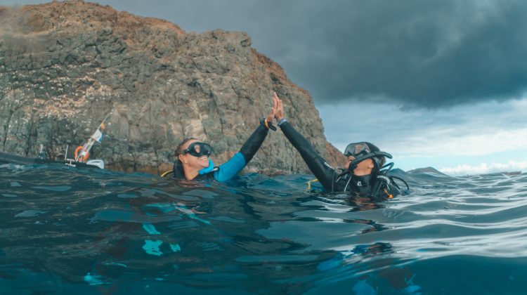 Two divers high fiving on the surface
