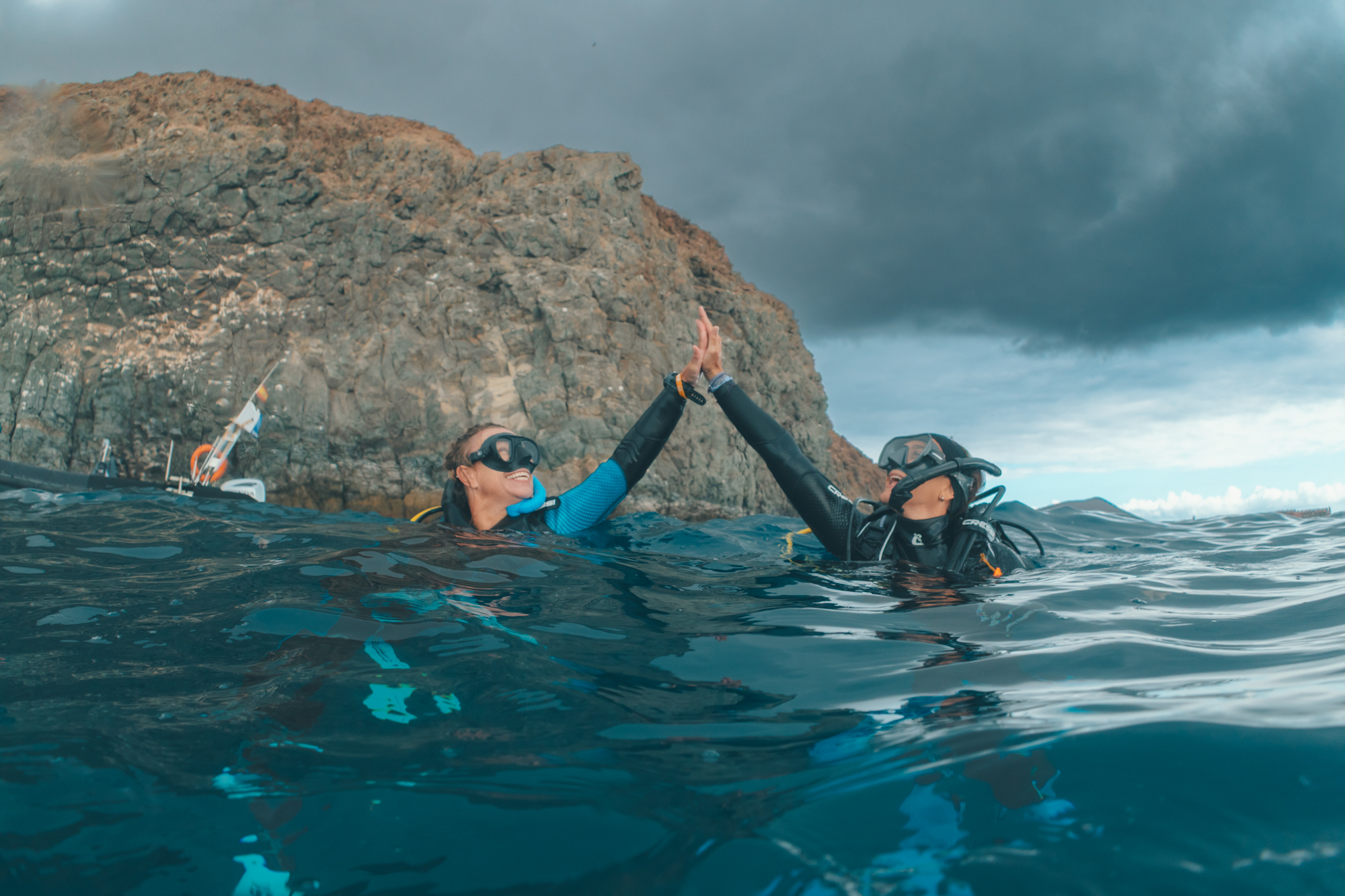 Two divers high fiving on the surface