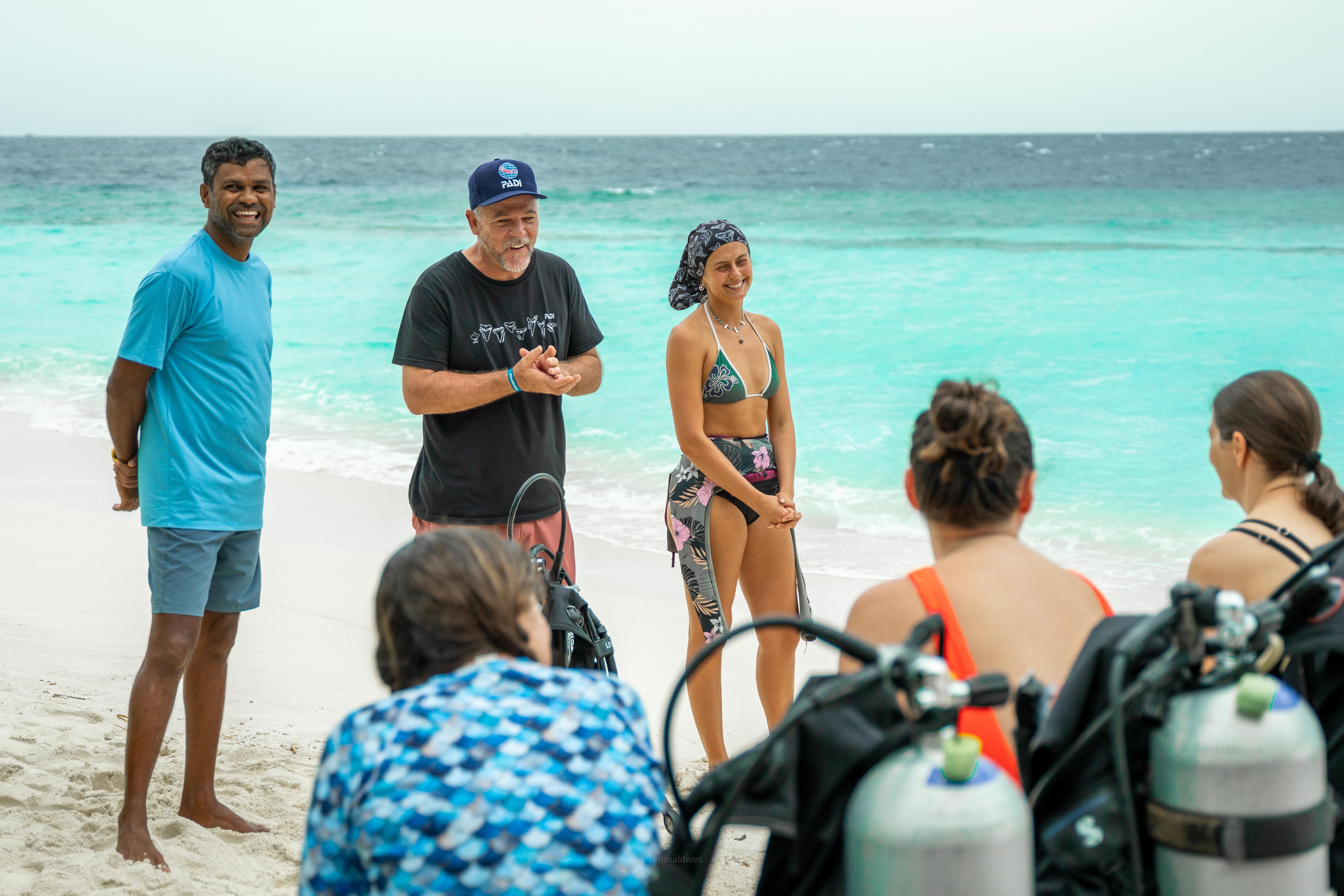 India Black stands with other diving professionals, addressing a group of divers.