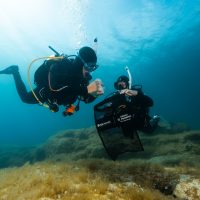 Two divers pick up debris during a dive against debris in Malta