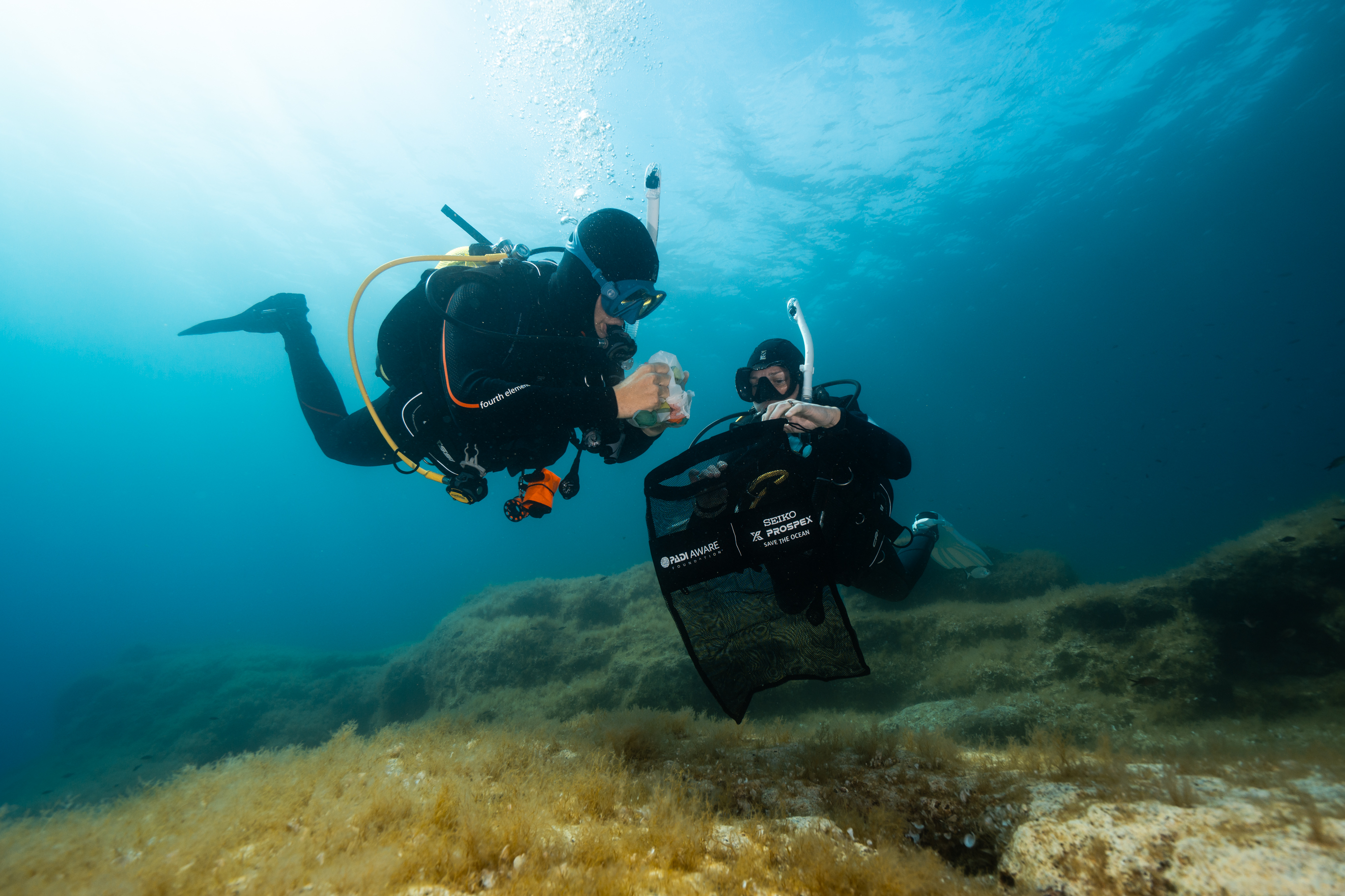Two divers pick up debris during a dive against debris in Malta