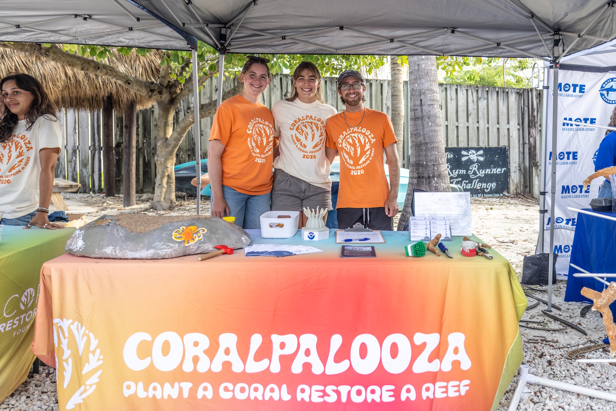 volunteers standing behind table during event. image courtesy of coralpalooza