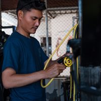 A PADI Pro checking scuba equipment regulators before going diving