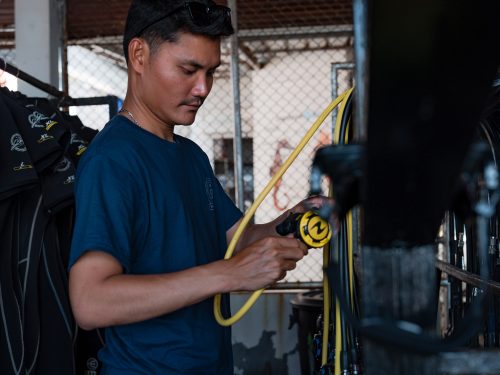 A PADI Pro checking scuba equipment regulators before going diving