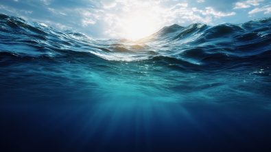Underwater view of the deep blue ocean, with sunlight filtering through to create ripples and waves. The water is calm yet powerful, representing both depth and serenity.