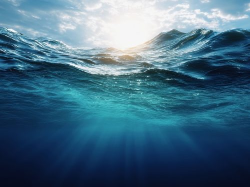 Underwater view of the deep blue ocean, with sunlight filtering through to create ripples and waves. The water is calm yet powerful, representing both depth and serenity.