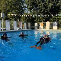 Students practicing a rescue exercise on the surface of the pool in full dive gear