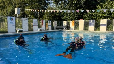 Students practicing a rescue exercise on the surface of the pool in full dive gear