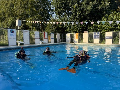 Students practicing a rescue exercise on the surface of the pool in full dive gear
