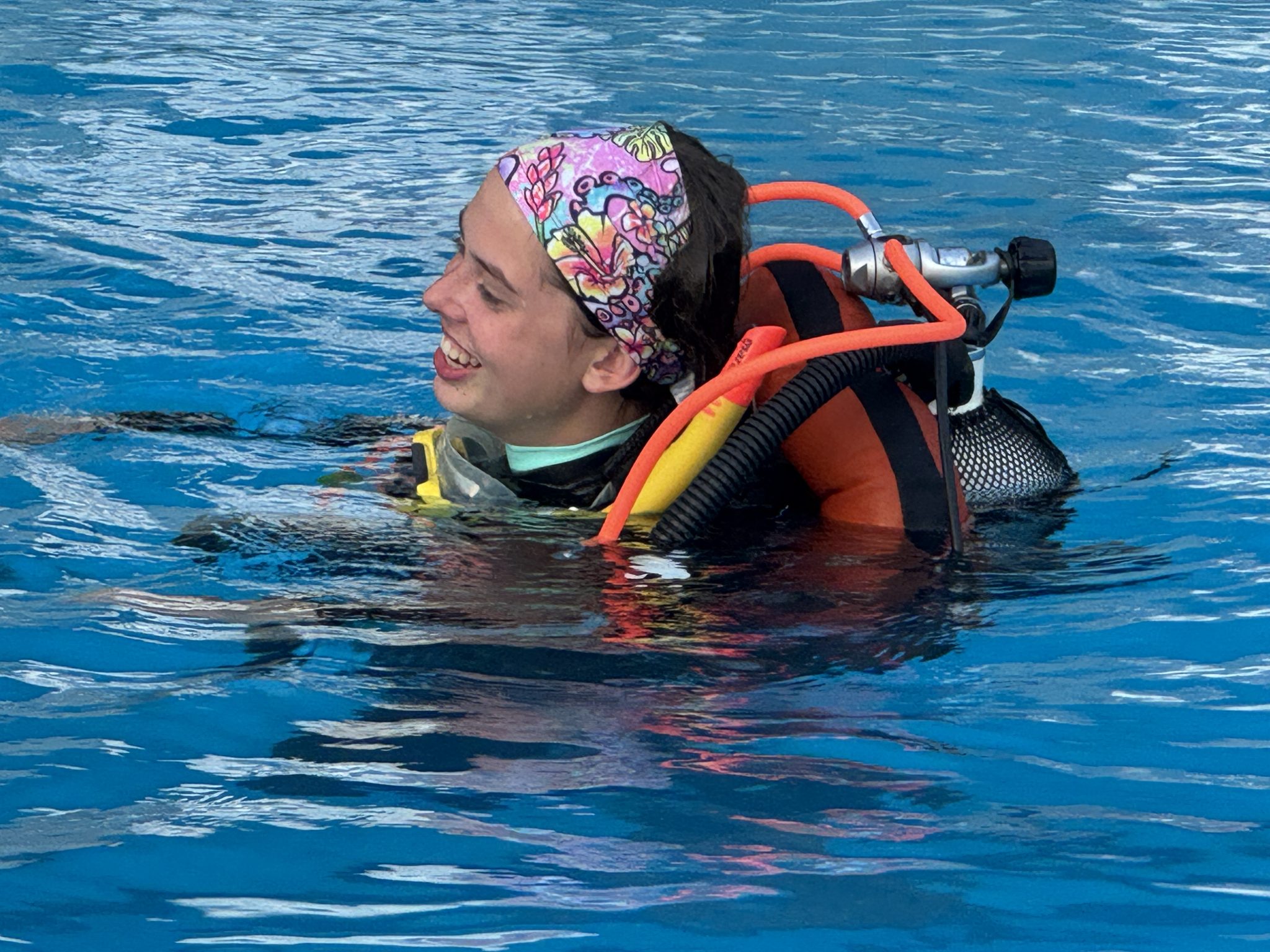 Diver in a pool in full gear posing on the surface with an inflated BCD