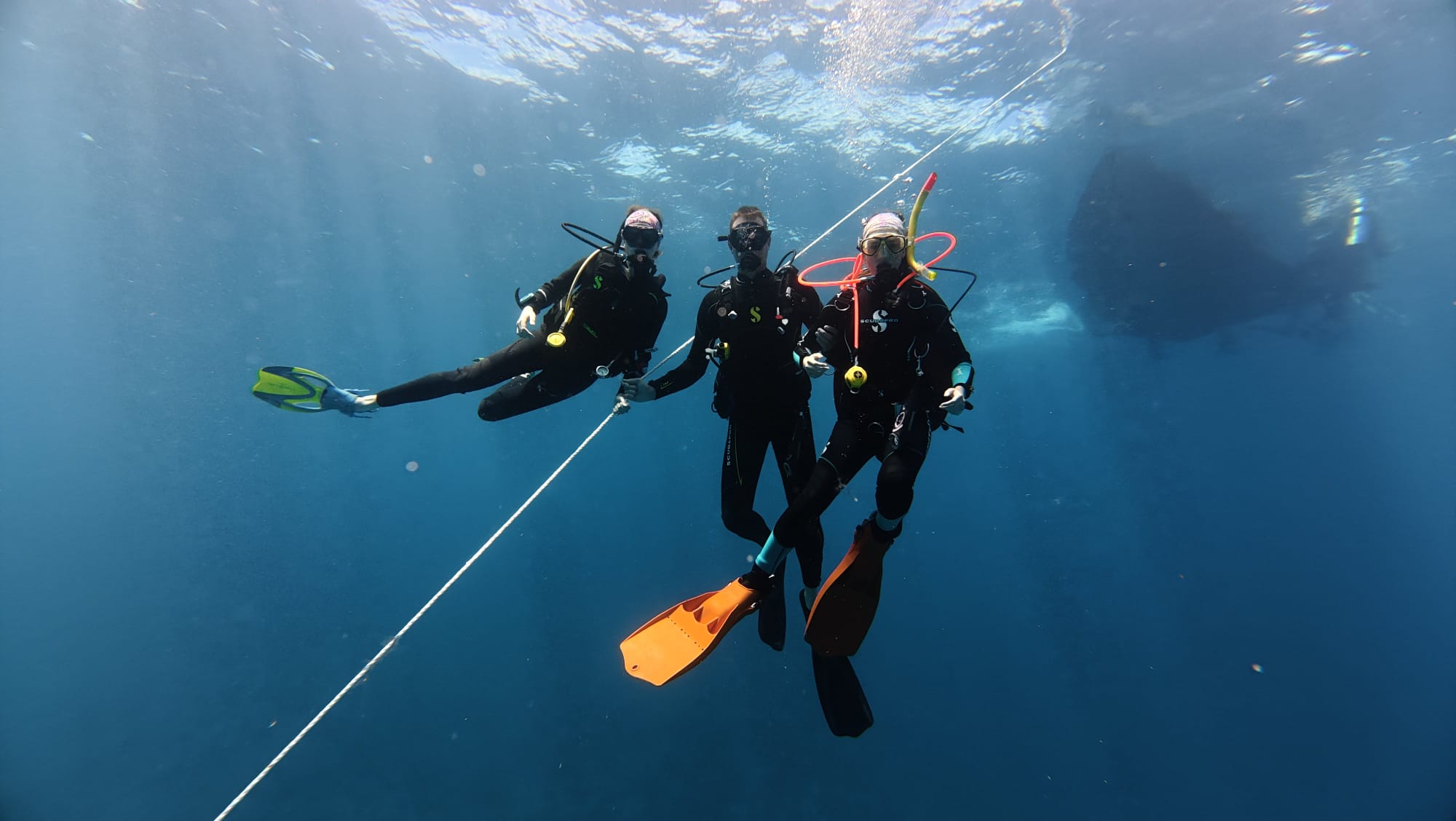 Three divers posing underwater next to an ascent line