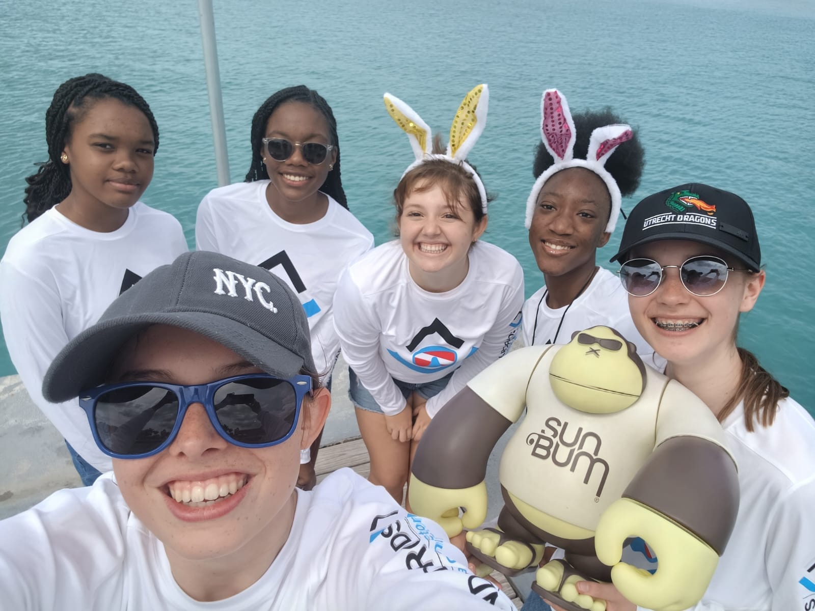 Six young girls from the Jr Divemaster program standing on a pier posing with sunglasses and bunny ears
