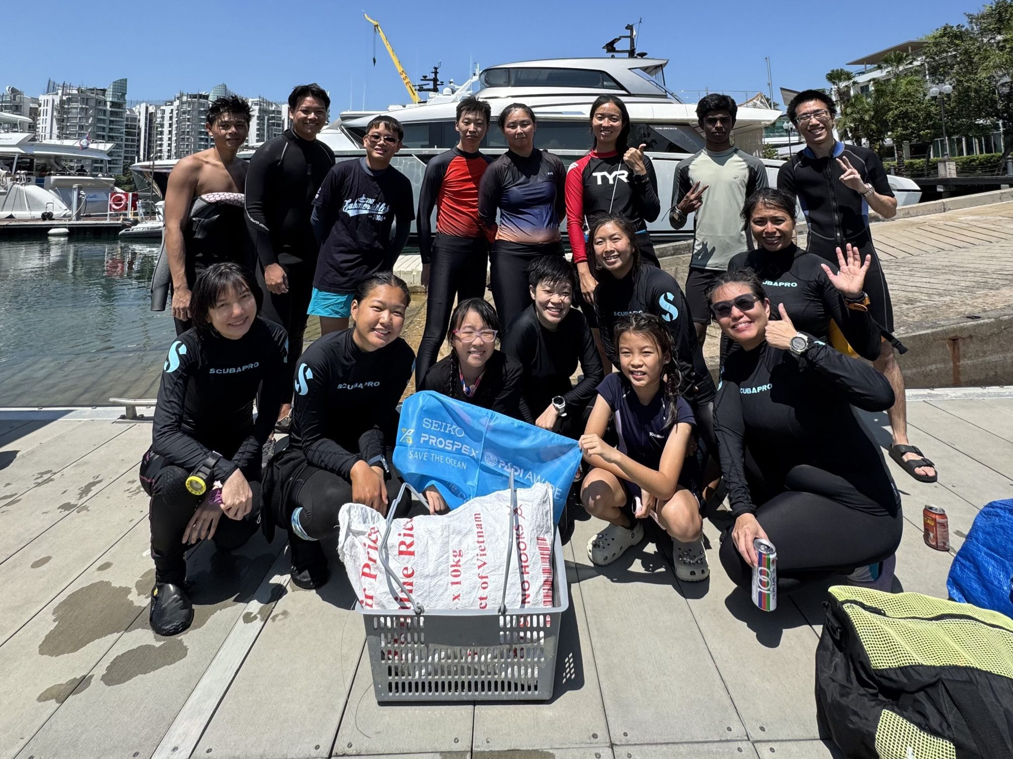 2026年「女性潛水日」海洋清理活動結束後，潛水員們在碼頭上以船隻為背景合影留念