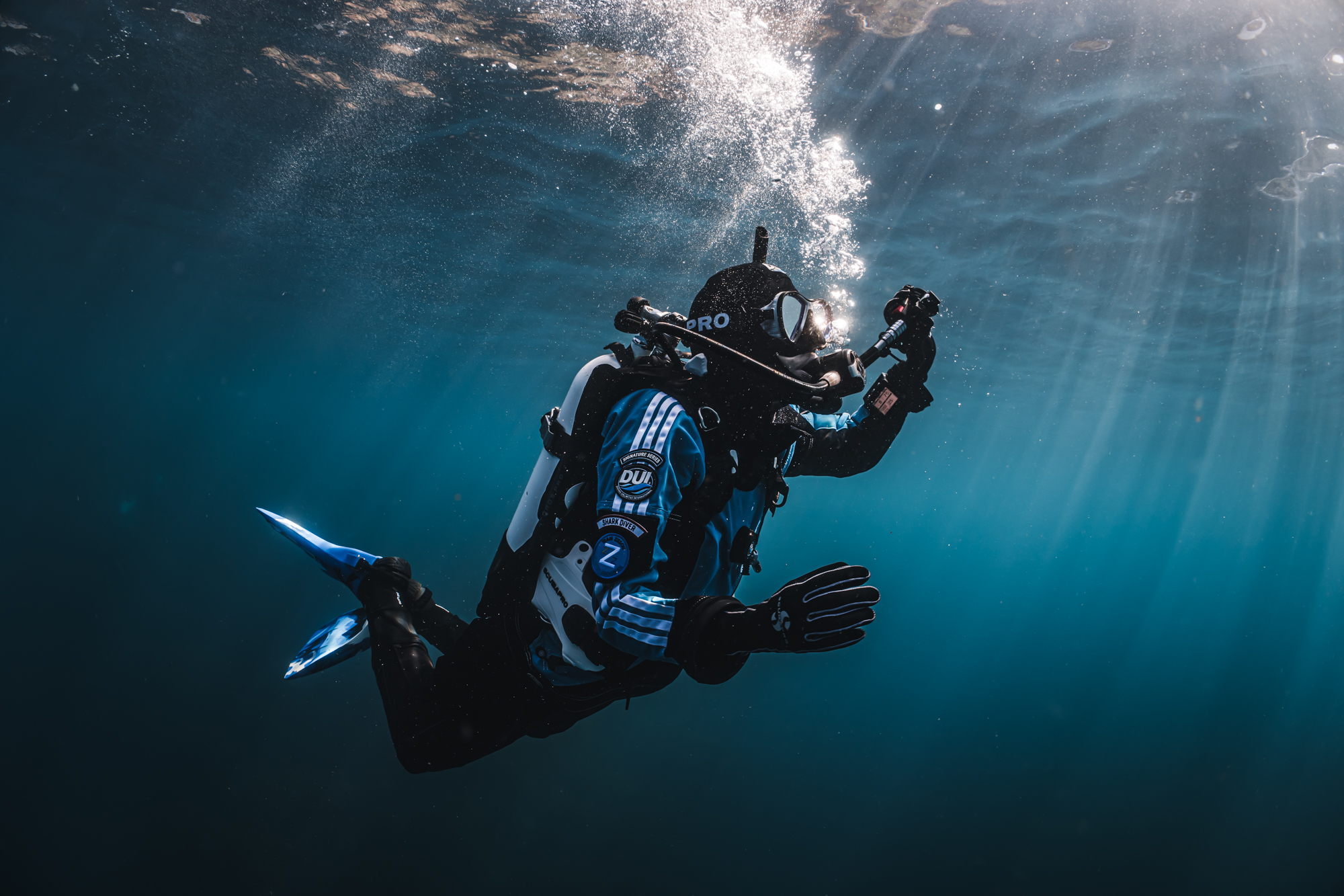 A drysuit diver breathing normally while ascending, which is an important part of how to ascend safely after a scuba dive