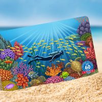 PADI certification card showing a coral garden propped up on a sandy beach