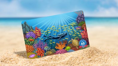 PADI certification card showing a coral garden propped up on a sandy beach