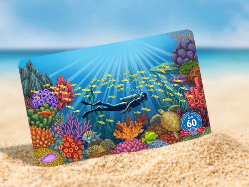PADI certification card showing a coral garden propped up on a sandy beach