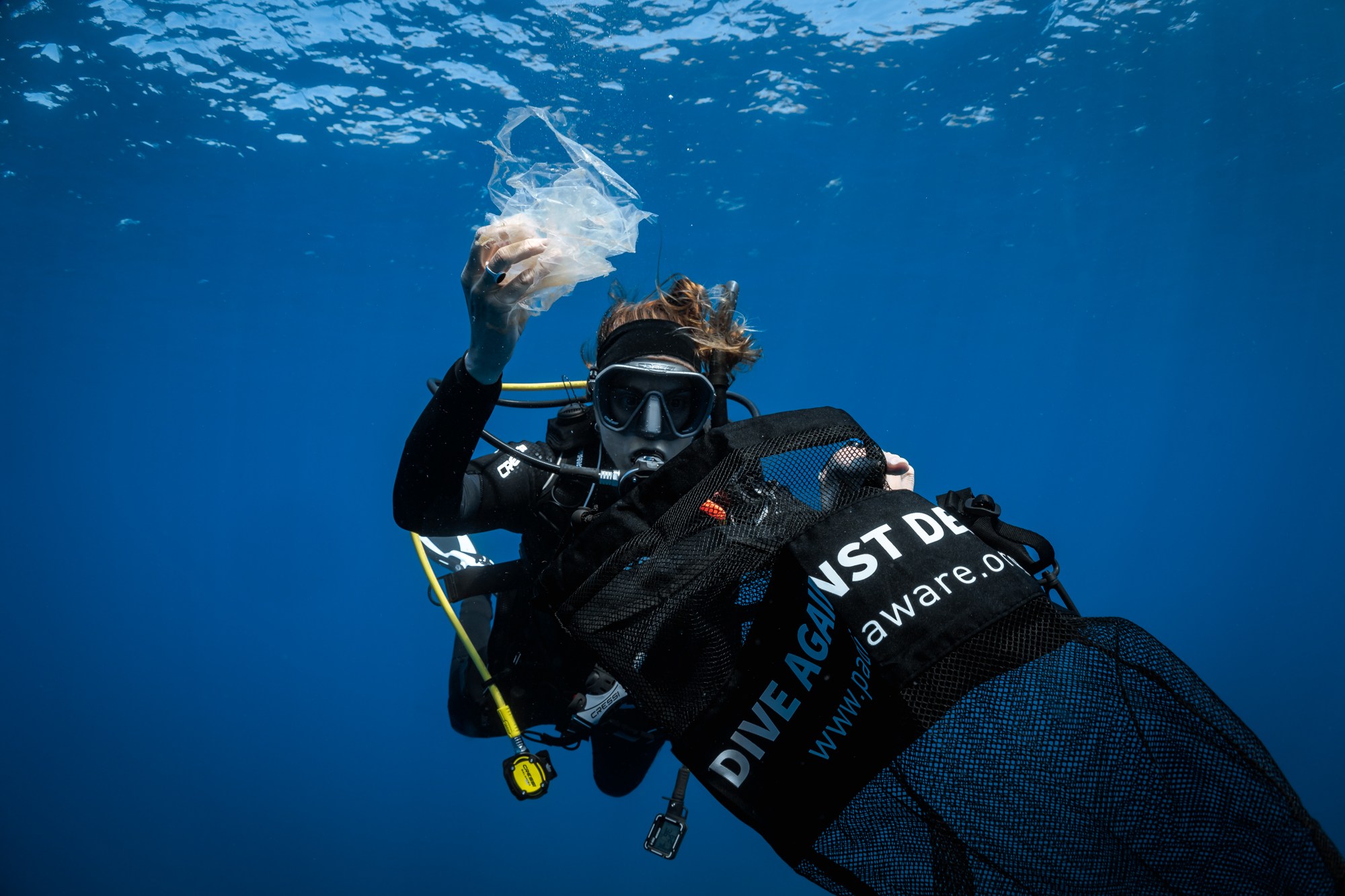 Diver picking up plastic to put in a Dive Against Debris bag