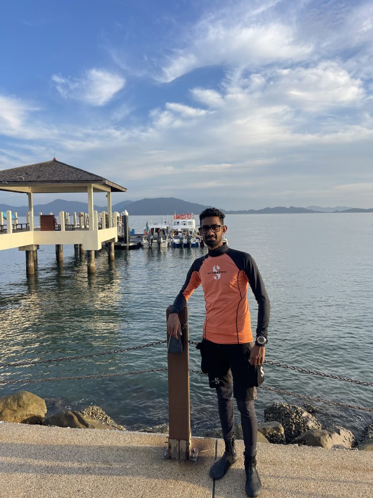 Sashaan Fernando standing on a dock in dive gear in Sri Lanka
