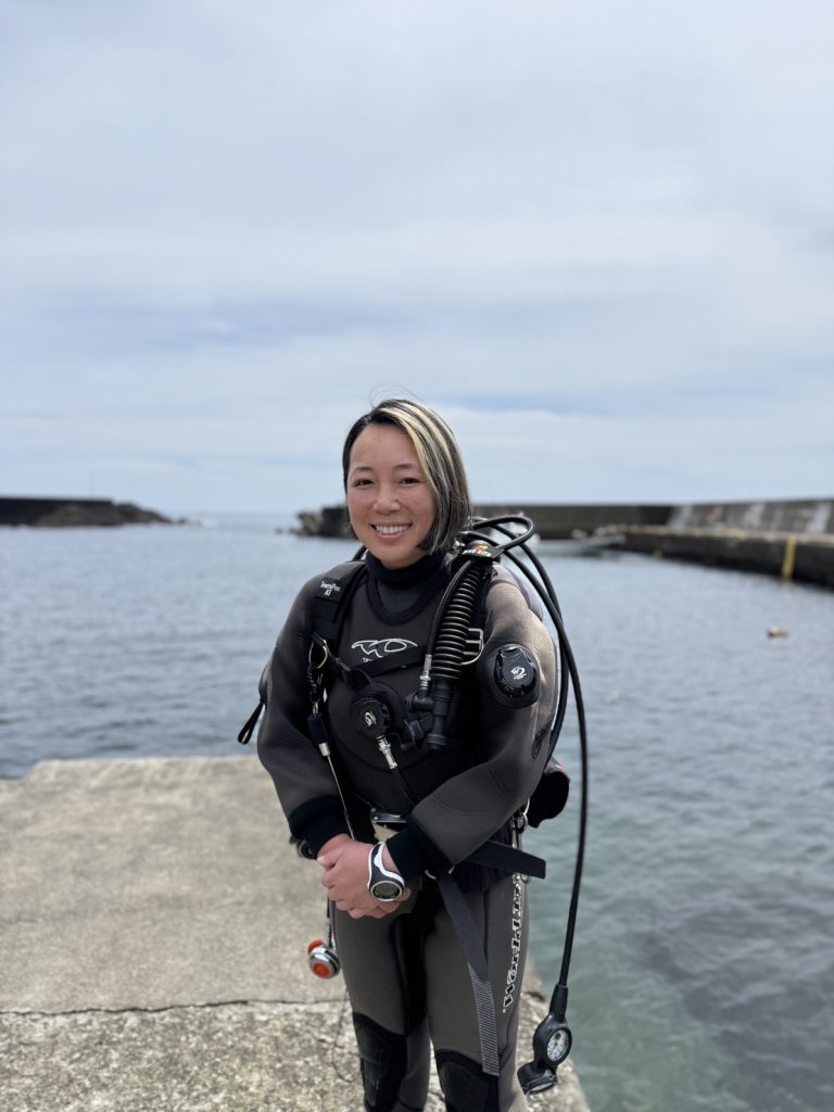 Ambassadiver & Ocean Torchbearer Award winner Yumi Shirai standing on a dock in full dive gear