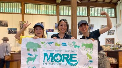 Ambassadiver Yumi Shirai in a classroom holding a sign with two other women for MORE school for conservation