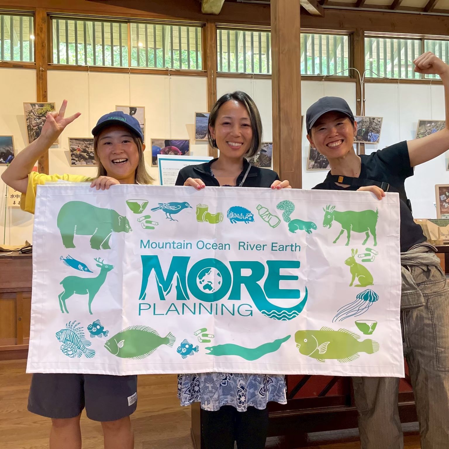 Ambassadiver Yumi Shirai in a classroom holding a sign with two other women for MORE school for conservation