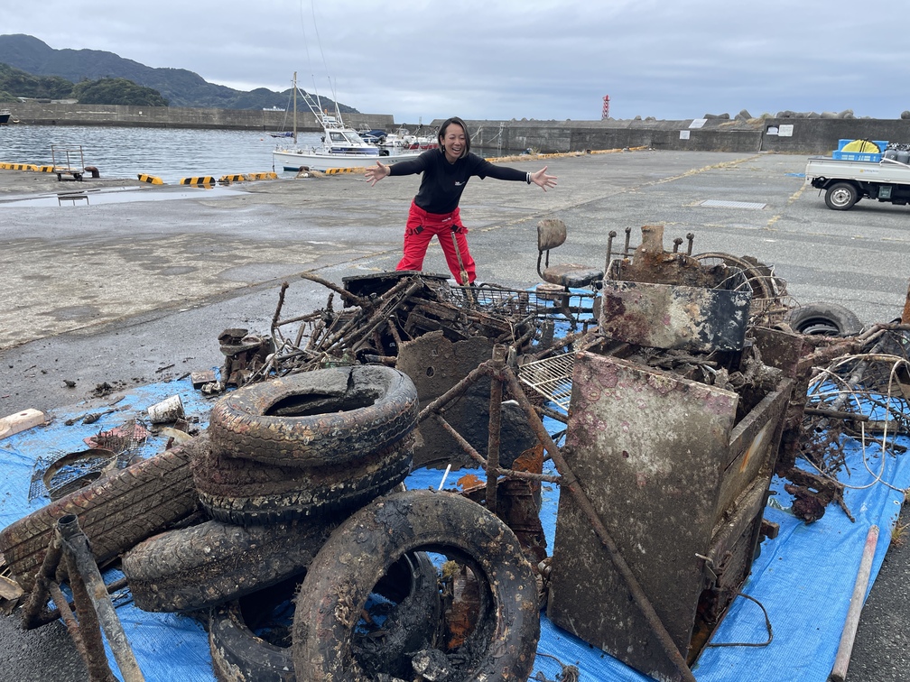Ambassadiver & Ocean Torchbearer Award winner Yumi Shirai on a dock among piles of marine debris