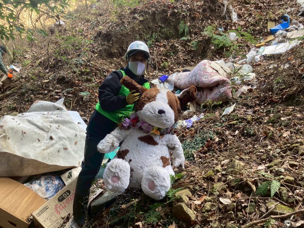 Ambassadiver & Ocean Torchbearer Award winner Yumi Shirai on a mountainside doing a cleanup among piles of debris