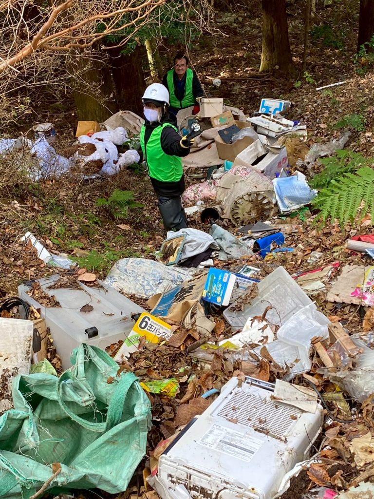 Ambassadiver & Ocean Torchbearer Award winner Yumi Shirai on a mountainside doing a cleanup among piles of debris