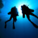 two divers using rebreathers descend from the ocean survace