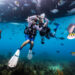 divers underwater in Belize make a heart shape with their arms