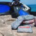 Scuba diving weights on rock by the ocean with equipment in background